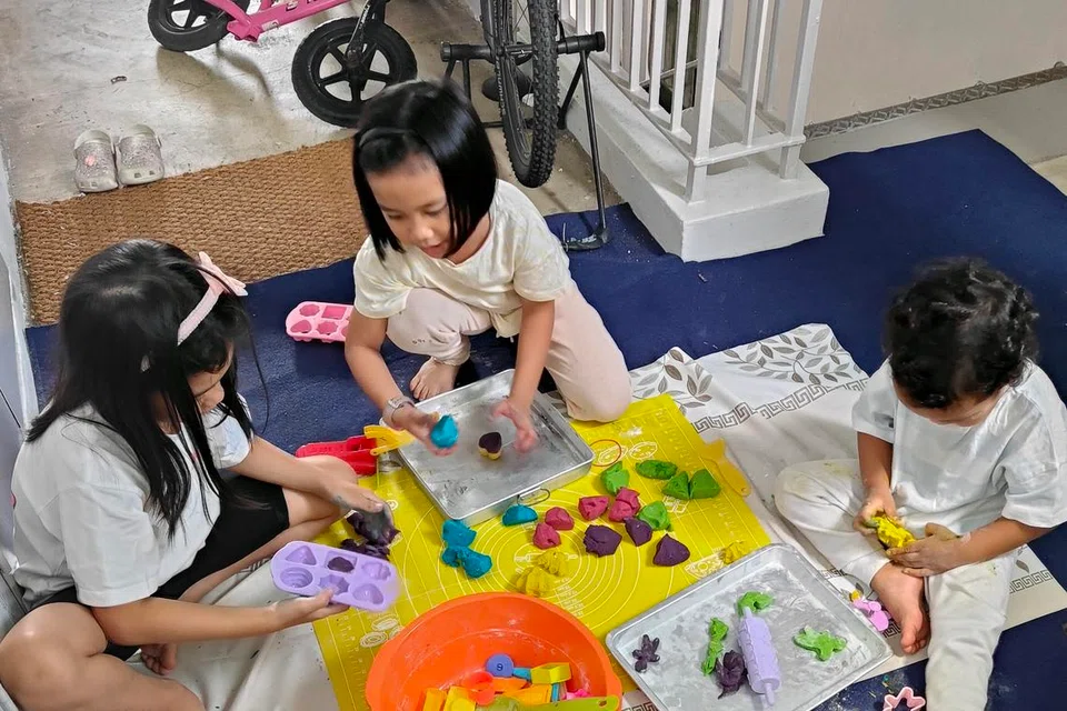 Anak-anak penulis, (dari kanan) Hamzah Mohammad Hanafi dan Munawwarah Mohammad Hanafi, bermain doh mainan yang dibuat sendiri bersama jiran mereka, Xena Lim, di koridor.