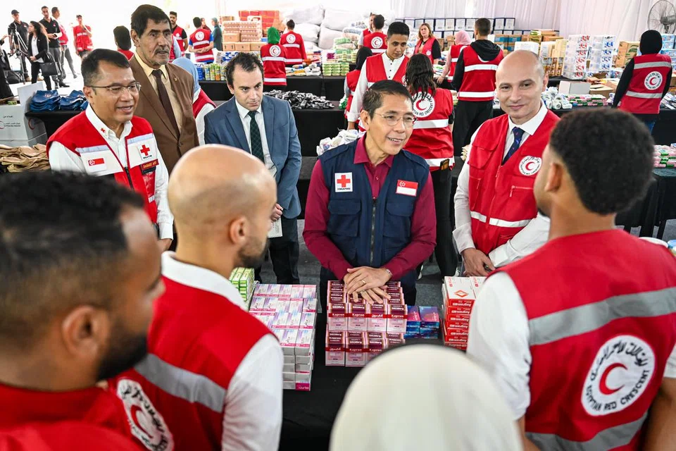 DEKATI KAKITANGAN: Menteri di Pejabat Perdana Menteri, Dr Mohamad Maliki Osman (tengah, jaket biru) bersama Encik Sahari Ani, Pengarah Kanan daripada Palang Merah Singapura (kiri, bercermin mata) dan Pengarah Eksekutif Persatuan Bulan Sabit Mesir (ERC), Dr Ramy El-Nazer, berinteraksi dengan para relawan dan kakitangan ERC.