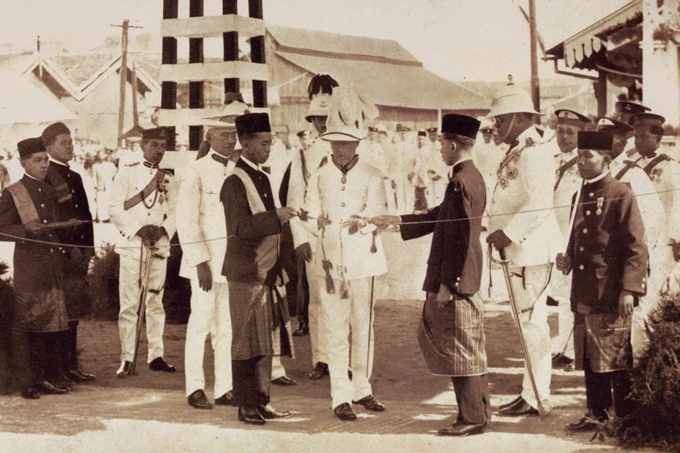 1924: Upacara pembukaan diadakan di Johor pada 28 Jun. Pada 9.15 pagi, Governor Guillemard (tengah) memotong reben kuning dengan gunting emas yang dihadiahkan oleh Sultan Ibrahim (dua dari kanan), melambangkan pembukaan rasmi tambak tersebut.