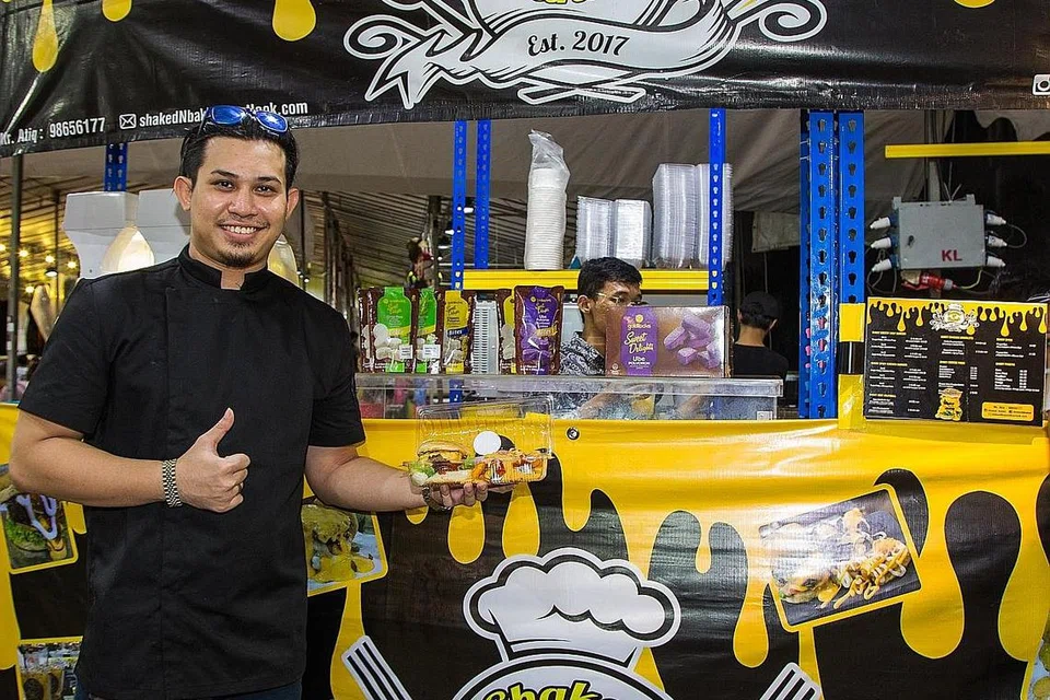 YAKIN JUALAN LAKU: Pemilik shakedNbaked, Encik Muhd Taufiq Hidayat Humdy, berjaya menjual purata 200 hingga 300 burger setiap hari pada minggu pertama perniagaannya di bazar Raya Geylang Serai dan berharap jumlah itu akan terus meningkat sepanjang bulan Ramadan ini. - Foto BM oleh ZALEHA ABDUL KADER