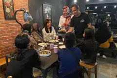 BERBUKA BERSAMA: Encik Moustaffa (kanan berdiri) bersama Cik Haslinda (dua dari kiri) dan Cik Alicia berinteraksi dengan salah satu keluarga yang hadir semasa acara iftar itu. - Foto HGEF