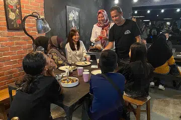 BERBUKA BERSAMA: Encik Moustaffa (kanan berdiri) bersama Cik Haslinda (dua dari kiri) dan Cik Alicia berinteraksi dengan salah satu keluarga yang hadir semasa acara iftar itu. - Foto HGEF