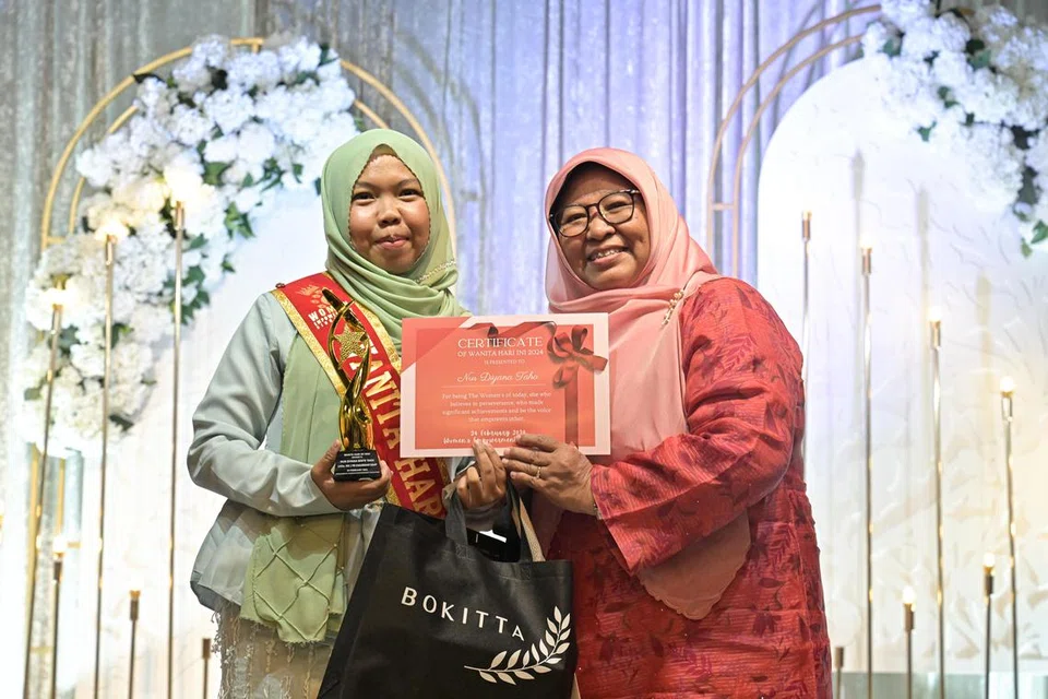 Cik Nur Diyana Taha, jurugambar Berita Harian (kiri), yang juga aktif dalam Persatuan Profesional Pentadbiran Singapura (SAAP), turut diberi pengiktirafan dengan anugerah disampaikan oleh mantan pengetua sekolah, Cik Aini Maarof. 