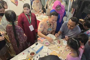 (Dari kanan) Encik  Zaqy Mohamad dan Encik Zhulkarnain Abdul Rahim menyertai kegiatan melukis batik yang dijalankan di salah satu reruai di Pesta Bahasa dan Budaya 2024 anjuran GRO Marsiling.