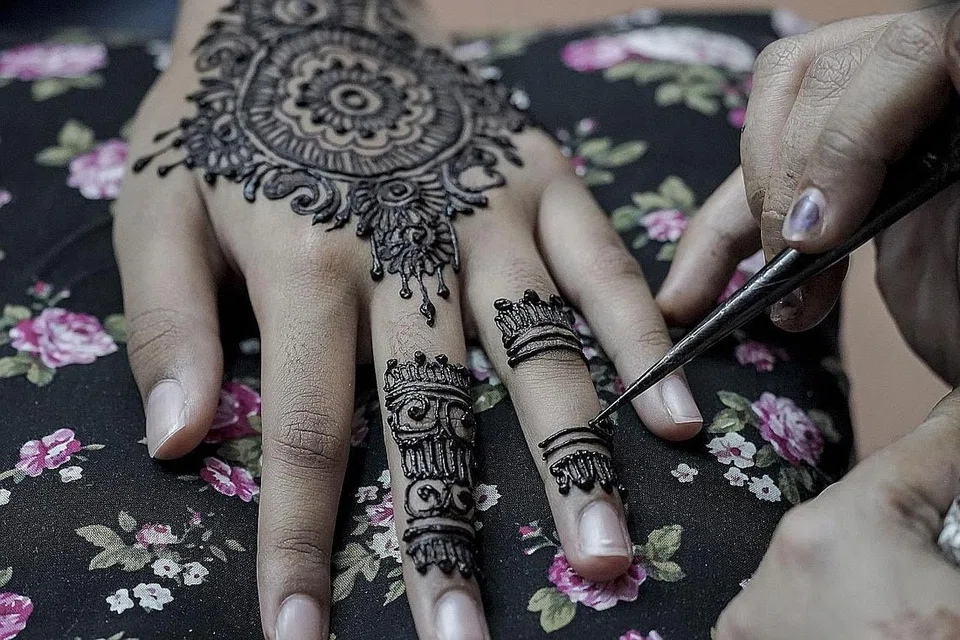 KEGIATAN PERAYAAN: Seorang gadis mendapatkan tatu inai di Little India sempena perayaan Deepavali. - Foto EPA-EFE 