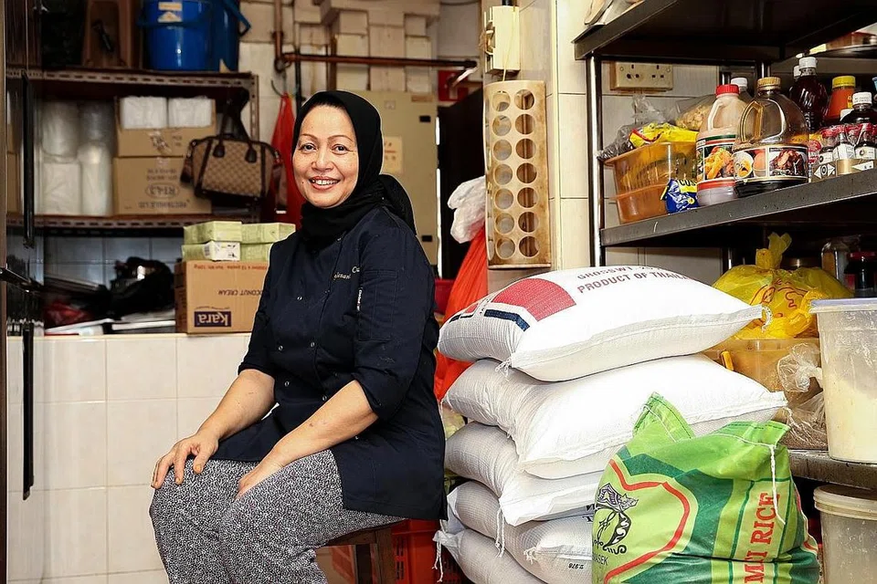 SEBAR KECERIAAN DENGAN BUBUR RAMADAN: Cik Rabiah bersama beras yang cukup untuk bertahan selama dua hingga tiga hari sewaktu pengagihan bubur percuma sewaktu Ramadan. Beliau tidak menyimpan stok untuk tempoh yang lama, dan lebih banyak guni beras akan dihantar nanti. - Foto BH oleh YONG LI XUAN