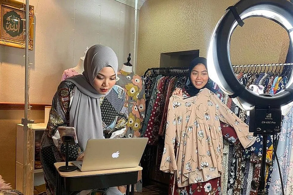 MENARIK PERHATIAN PELANGGAN: Melalui wadah Instagram Live di hijabifiedsg, Cik Aliah (kiri) dan adiknya, Cik Ayuni, dapat menarik perhatianpelanggan dengan menunjukkan baju yang dijual serta memaklumkan dengan lebih lanjut kepada pelanggan mengenai pakaian yang mereka berminat. - Foto ihsan NURUL ALIAH NIZAM