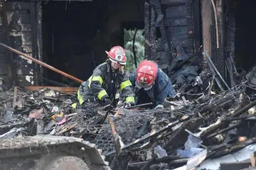 Anggota bomba mencari di puing rumah tiga tingkat di Baltimore, Maryland, yang dijilat api, menyebabkan enam kanak-kanak adik-beradik terbunuh dan ibu serta tiga lagi adik-beradik mereka cedera. 