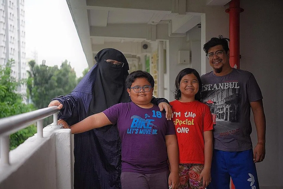 BANTUAN UNTUK KELUARGA: Cik Nursheila (kiri) dan dua anaknya yang berusia 11 dan 10 tahun bergantung pada suaminya, Encik Zulhaider Anang (kanan), yang bertugas sebagai pekerja penghantaran Grab Food. Namun dengan adanya bantuan inisiatif Community Link (ComLink), mereka diberi kelegaan. - Foto BH oleh MARK CHEONG