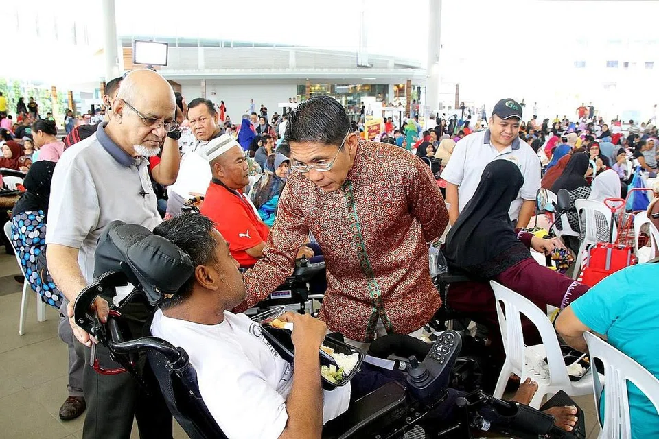 UTAMAKAN KESIHATAN: Dr Maliki (berbaju batik) dengan diiringi Pengurus Kanan Dana Pengamanah TAA, Encik Yahya Zakaria (kiri), menghadiri Karnival Kesihatan anjuran TAA semalam di Bedok Town Square. - Foto TAA