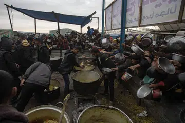 Kanak-kanak dan penduduk Palestin di Khan Younis, di selatan Gaza Selatan, mengharapkan makanan dari dapur amal pada 29 November. Lebih 1.8 juta penduduk Gaza kini berdepan kekurangan makanan kritikal dengan 133,000 daripadanya mengalami tahap kebuluran.