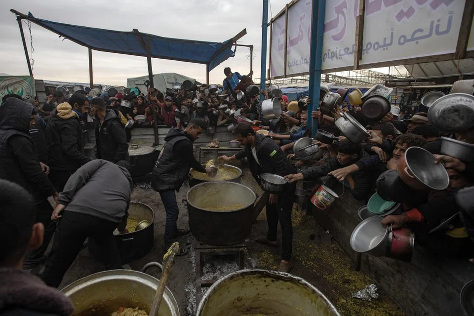 Kanak-kanak dan penduduk Palestin di Khan Younis, di selatan Gaza Selatan, mengharapkan makanan dari dapur amal pada 29 November. Lebih 1.8 juta penduduk Gaza kini berdepan kekurangan makanan kritikal dengan 133,000 daripadanya mengalami tahap kebuluran.