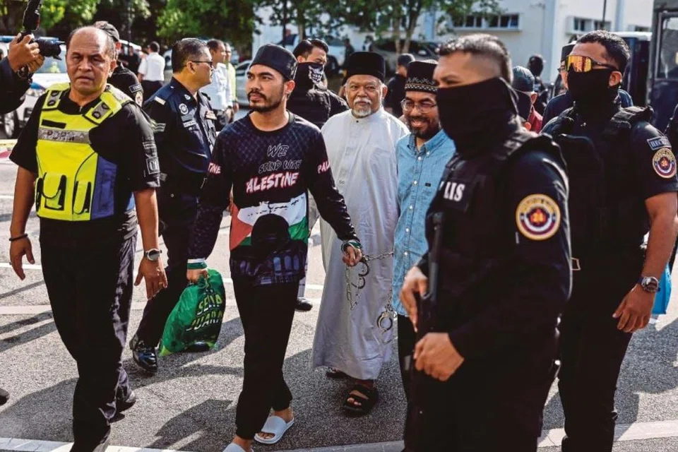 Ketua Pegawai Eksekutif (CEO) Global Ikhwan Service and Business Holdings (GISBH), Nasiruddin Mohd Ali (tiga dari kanan), bersama 21 pengikut kumpulan itu, termasuk isterinya dan anak lelaki pengasas Al-Arqam, didakwa menjadi anggota kumpulan jenayah terancang di Mahkamah Sesyen Selayang, Selangor, pada 23 Oktober.