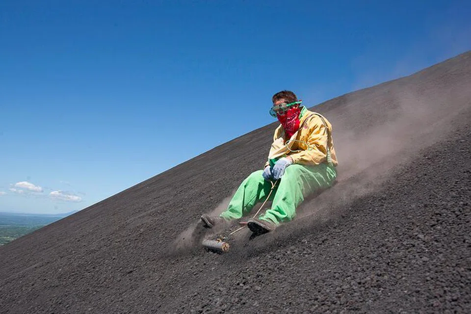 LUNCUR ATAS GUNUNG BERAPI: Seorang pelancong seronok meluncur laju di Gunung Berapi Cerro Negro.