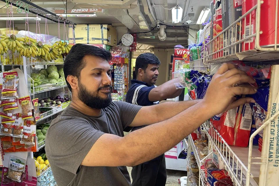 KENDALIKAN KEDAI: Encik Abdul Wahid Haji Sultan (kemeja-T biru, di belakang) telah mengendalikan urusan operasi kedai runcit bawah blok milik mak ciknya di Holland Close sejak lebih sedekad lalu, dibantu oleh sepupunya yang lain seperti Encik Mohamed Yasir Basir Ahmad (depan).