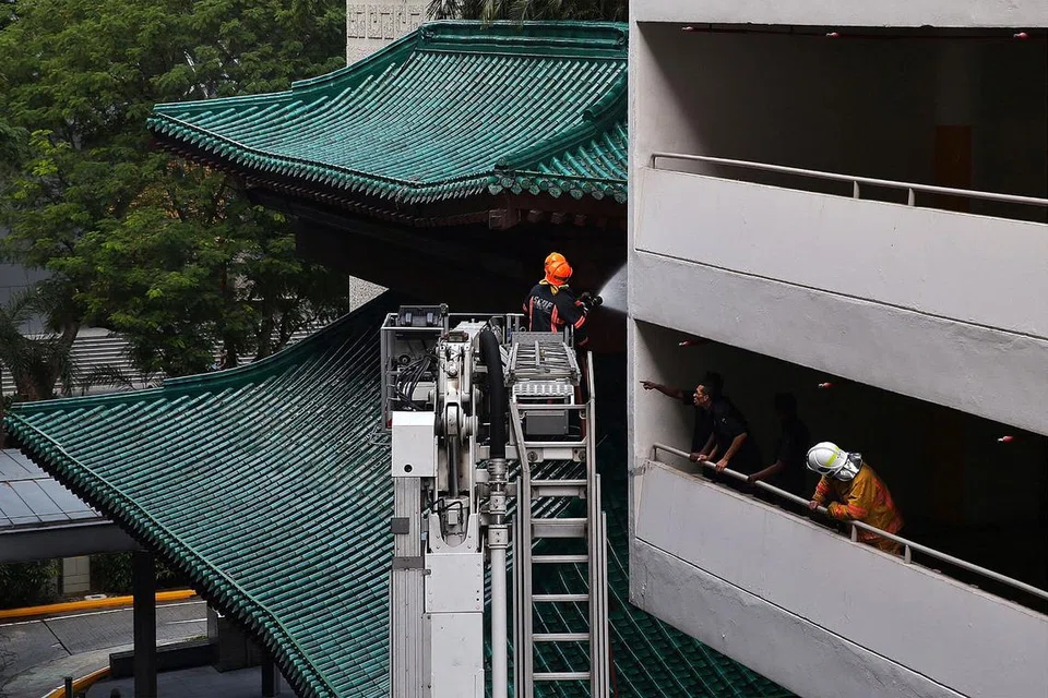 MENINJAU KESAN KEBAKARAN: Anggota Pasukan Pertahanan Awam Singapura (SCDF) meninjau kesan kebakaran yang berlaku di Hotel Marriott Tang Plaza. - Foto THE STRAITS TIMES