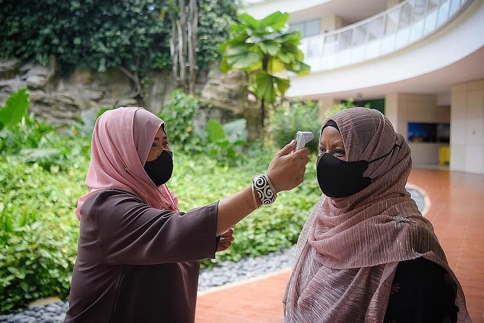 PASTIKAN KESELAMATAN: Cik Juliana Maktob sedang mengambil suhu badan tetamu yang hadir. - Foto BM oleh MARK CHEONG