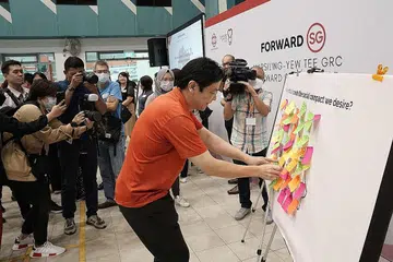 SUARAKAN HALA TUJU: Encik Wong menampal nota 'post-it' di papan tanda yang mengajak para peserta menulis keinginan mereka untuk kompak sosial baru Singapura. - Foto GRC MARSILING-YEW TEE