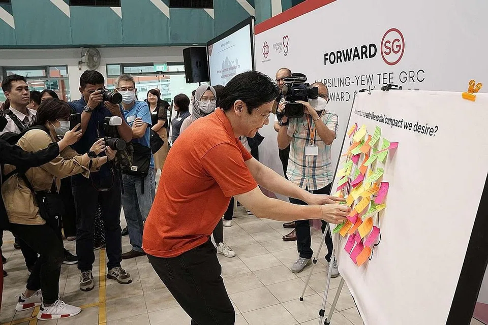 SUARAKAN HALA TUJU: Encik Wong menampal nota 'post-it' di papan tanda yang mengajak para peserta menulis keinginan mereka untuk kompak sosial baru Singapura. - Foto GRC MARSILING-YEW TEE