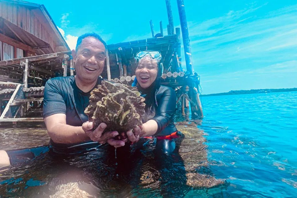 Wartawan Cik Rubiah Mohd bersama suami, Encik Naguib Helmy (kiri) bergambar dengan kerang gergasi yang masih hidup semasa aktiviti snorkel di Bintan.
