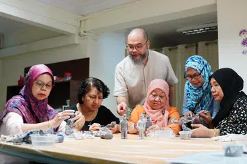 Encik Raihan Harun membimbing peserta mengukir tanah liat menjadi patung askar kontinjen Kawalan Kehormatan Perbarisan Hari Kebangsaan (NDP) masa lalu, bagi ‘National Antiquities Parade’, iaitu pameran interaktif semasa Minggu Seni Singapura. 