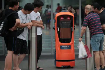ERA TEKNOLOGI DAN AUTOMASI: Pengunjung di Jewel Lapangan Terbang Changi melihat secara dekat robot autonomi kendalian Certis Cisco pada 4 Jun lalu. Menurut penulis, rakyat Singapura perlu belajar untuk bekerja bersama robot untuk melangkah lebih jauh ke hadapan. - Foto BH oleh JASON QUAH