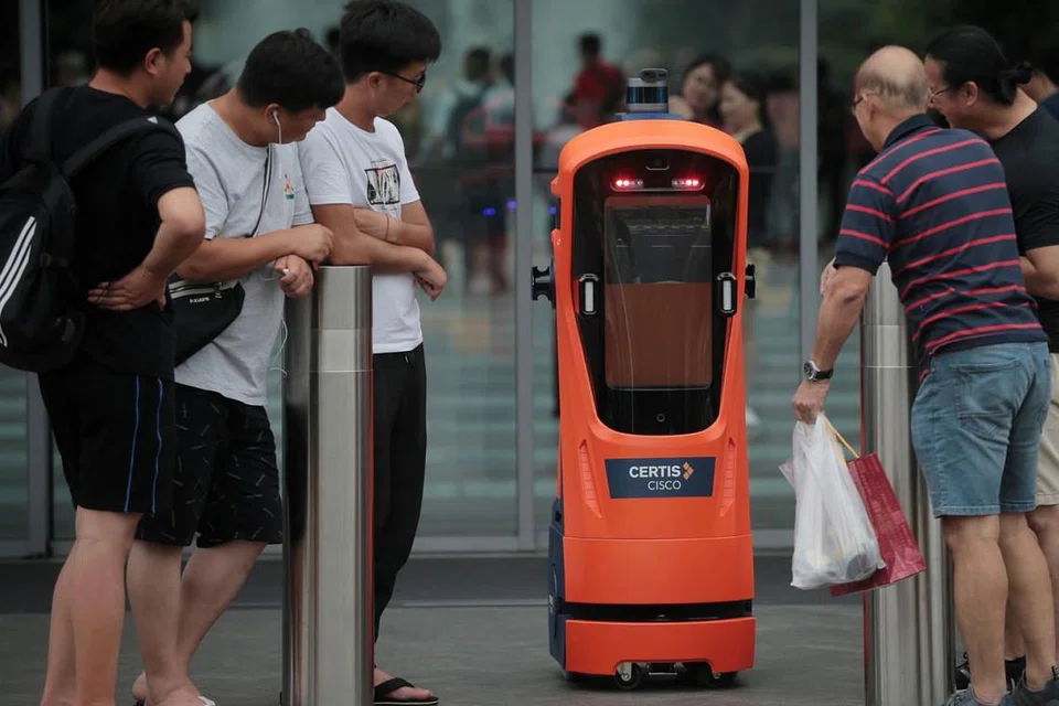 ERA TEKNOLOGI DAN AUTOMASI: Pengunjung di Jewel Lapangan Terbang Changi melihat secara dekat robot autonomi kendalian Certis Cisco pada 4 Jun lalu. Menurut penulis, rakyat Singapura perlu belajar untuk bekerja bersama robot untuk melangkah lebih jauh ke hadapan. - Foto BH oleh JASON QUAH