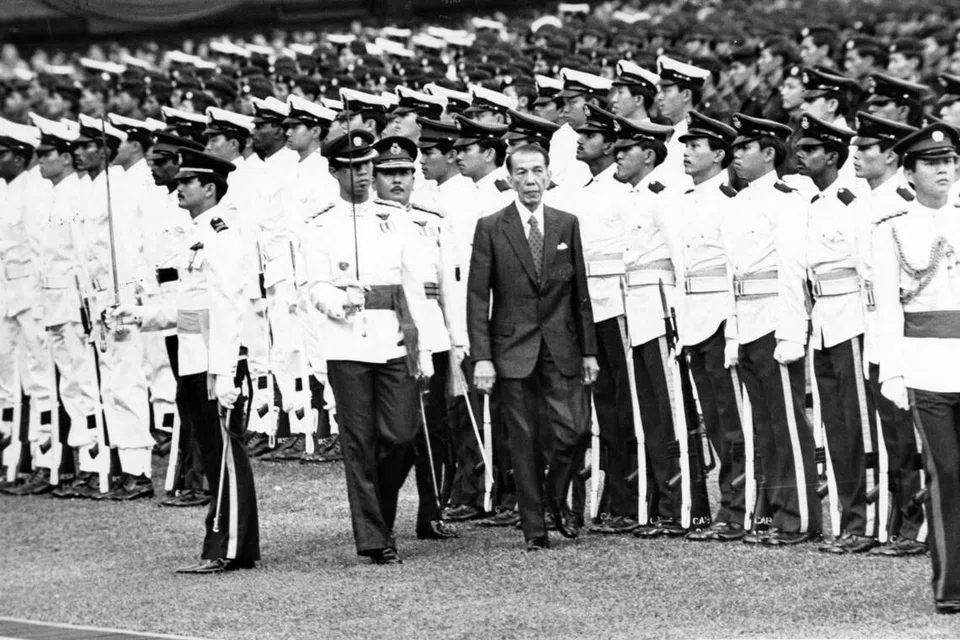 Presiden Singapura ke-2, Dr Benjamin Sheares (memakai sut hitam), memeriksa Kawalan Kehormatan semasa NDP yang diadakan di Stadium Negara pada 9 Ogos 1980. Turut kelihatan di belakang beliau ialah Ketua Staf Am Angkatan Bersenjata Singapura (SAF) ketika itu, Mejar-Jeneral Winston Choo.