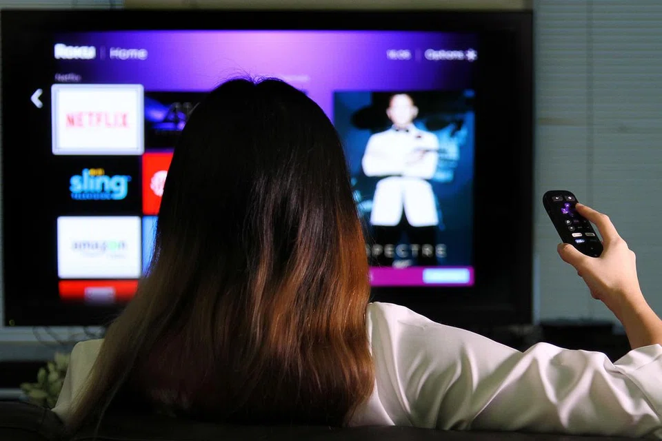 DIBELENGGU BANYAK ISU: Seorang wanita menonton program menggunakan Netflix yang menawarkan khidmat 'streaming' atau aliran cepat rancangan siri televisyen dan filem menerusi Internet. - Foto THE STRAITS TIMES