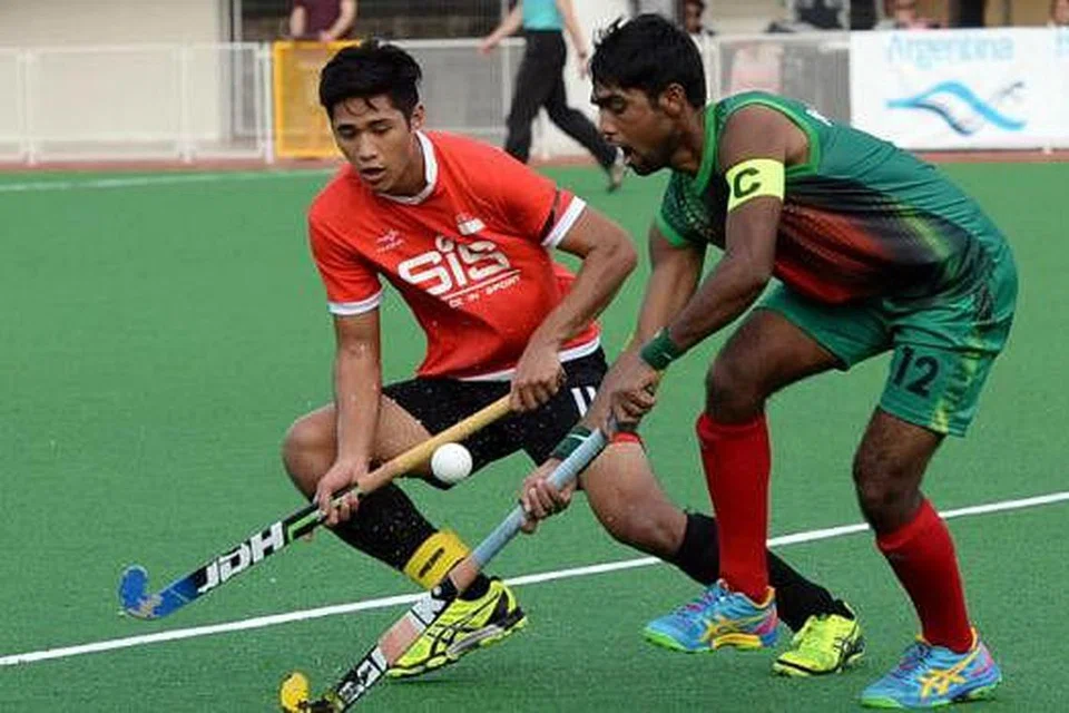 REBUT BOLA: Tunggak midfield Singapura, Ashriq Ferdaus (jersi merah), bersaing bola dengan kaptain Bangladesh, Kumar Das Krisno, dalam pertemuan Liga Dunia di Stadium Sengkang semalam. - Foto ZAINAL YAHYA