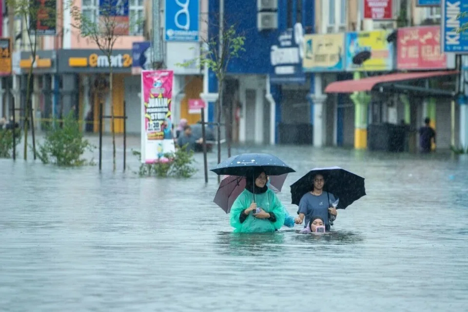 Orang awam keluar dari kawasan banjir di Pengkalan Chepa, Kelantan, pada 23 November.