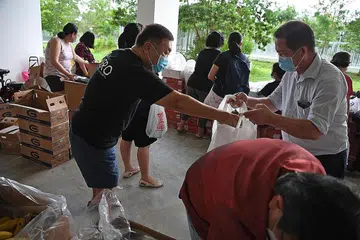 USAH MEMBAZIR: Encik Ong (kiri) mengagihkan anggur yang 'diselamatkan' kepada penduduk di Blok 415C Fernvale Link. - Foto BM oleh DESMOND FOO