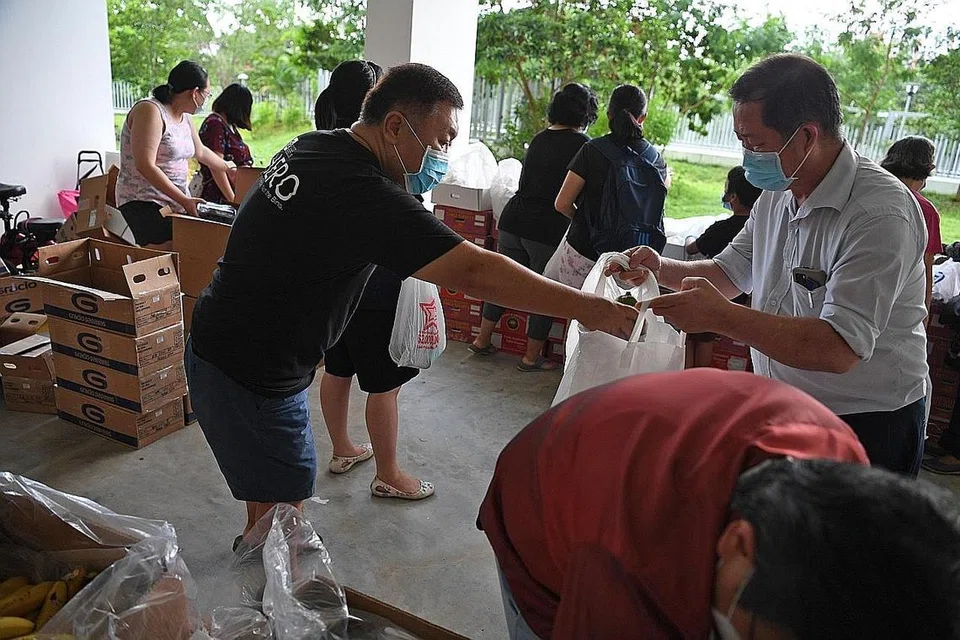 USAH MEMBAZIR: Encik Ong (kiri) mengagihkan anggur yang 'diselamatkan' kepada penduduk di Blok 415C Fernvale Link. - Foto BM oleh DESMOND FOO