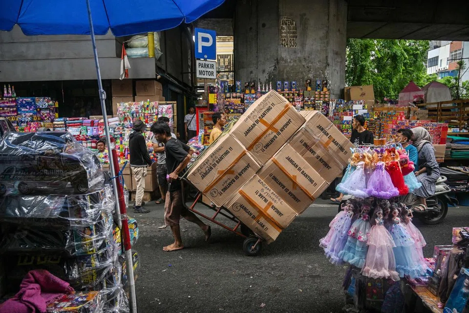 Seorang pekerja menarik troli berisi barangan di sepanjang jalan pasar borong di Jakarta pada 17 Disember sedang pemerintah Indonesia  mengumumkan langkah ekonomi untuk meredakan kesan kenaikan kadar cukai nilai tambah (VAT).