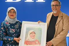 MENGHARGAI USAHA: Encik Samad Afandie (kanan) menghadiahkan potret kepada Puan Halimah Yacob di majlis jamuan di pejabat Berita Harian.