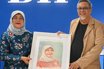 MENGHARGAI USAHA: Encik Samad Afandie (kanan) menghadiahkan potret kepada Puan Halimah Yacob di majlis jamuan di pejabat Berita Harian.