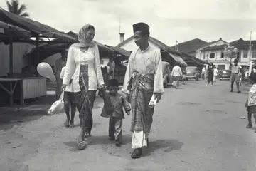 Encik Suhaimi Samian (kanan) bersama isteri dan anaknya pulang ke rumah mereka di kawasan Geylang Serai selepas pergi kunjung-mengunjung pada Hari Raya. Gambar ini diambil sekitar tahun 60-an. 