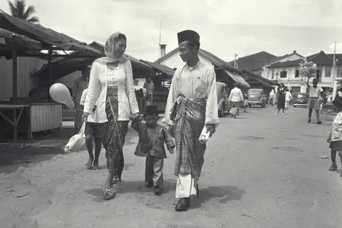 Encik Suhaimi Samian (kanan) bersama isteri dan anaknya pulang ke rumah mereka di kawasan Geylang Serai selepas pergi kunjung-mengunjung pada Hari Raya. Gambar ini diambil sekitar tahun 60-an. 