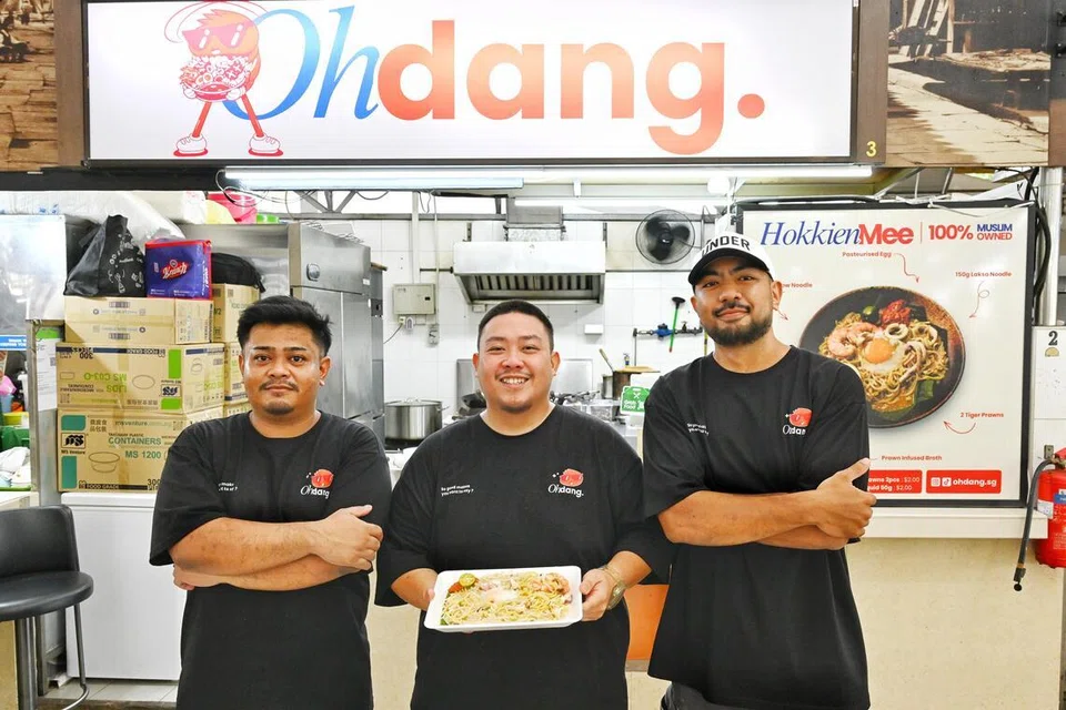 Pemilik Ohdang, Encik Ryan Nabil Tan (tengah), bersama pasukannya, Encik Muhd Zulfaizal Selamat, dan Encik Muhd Muhaimin Abdul Raof Magad, di gerai Ohdang mereka yang terletak di kawasan perindustrian Marsiling.