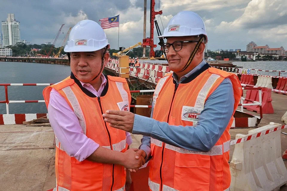 TINJAU PERKEMBANGAN PROJEK: Menteri Pengangkutan, Encik S Iswaran (kanan), berjabat tangan dengan Menteri Pengangkutan Malaysia, Encik Anthony Loke, di atas jejambat pembinaan laluan RTS di sebelah Malaysia.