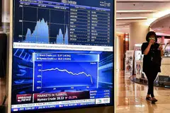 EKONOMI MERUDUM: Papan elektronik yang dipasang di sebuah pusat beli-belah di Bangkok semalam menunjukkan saham Asia merosot sedang harga minyak dilaporkan menjunam. - Foto AFP