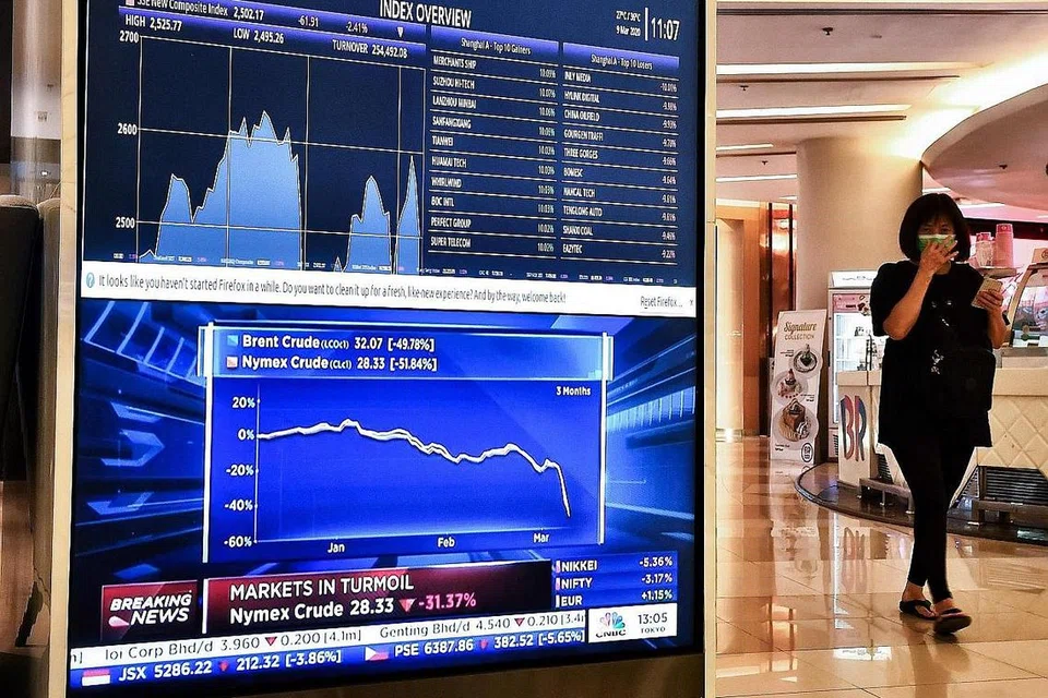 EKONOMI MERUDUM: Papan elektronik yang dipasang di sebuah pusat beli-belah di Bangkok semalam menunjukkan saham Asia merosot sedang harga minyak dilaporkan menjunam. - Foto AFP