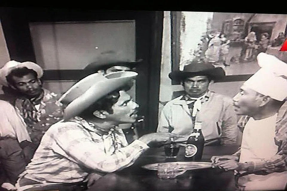 PERANG KOBOI: Dalam babak berangan-angan hebat, si tukang gaji dalam filem Labu Labi, lakonan M. Zain membayangkan dirinya sebagai Jesse Labu (sepupu penjahat dunia Barat di alam nyata, Jesse James) yang kini ingin menewaskan Haji Bakhil yang sombong dan kedekut. - Foto SHAW ORGANISATION