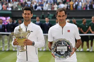 JUARA LALU: Juara Wimbledon 2019, Novak Djokovic (kiri) bersama naib juara Roger Federer, bergambar selepas menerima trofi mereka di akhir satu pertarungan sengit tahun lalu. - Foto AFP