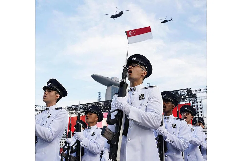 MAJULAH SINGAPURA: Kontinjen kawalan kehormatan dari Pasukan Polis Singapura (SPF) menyanyikan Lagu Kebangsaan ketika dua helikopter Chinook yang membawa bendera negara dan diiringi helikopter Apache di The Float@Marina Bay.