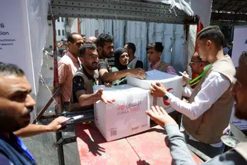 Penduduk Palestin menerima bungkusan makanan sumbangan Amiriah Arab Bersatu (UAE) dari pusat pengagihan yang diawasi oleh sukarelawan dalam kalangan keluarga Palestin yang membentuk jawatankuasa khas bagi mengelakkan kejadian kecurian, di Bandar Gaza pada 26 Jun 2025.