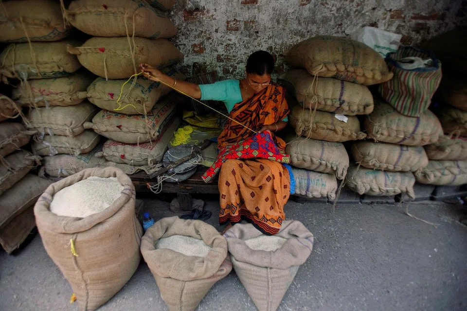 HARGA BERAS TERUS MENINGKAT: Seorang pekedai sedang menjahit di pasar borong beras di bandar Kolkata di timur India. 