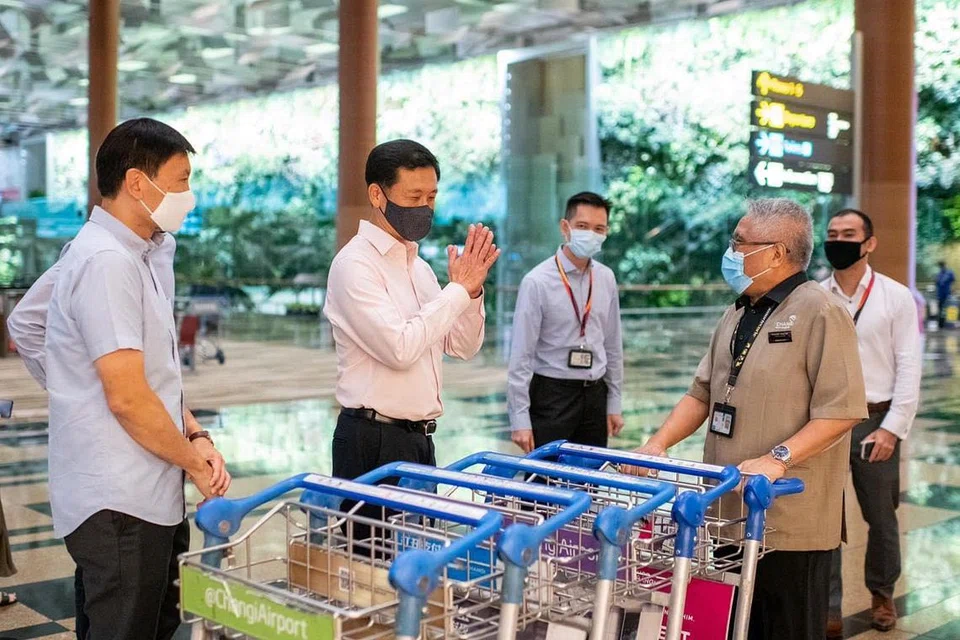 TINJAU LAPANGAN TERBANG CHANGI: Menteri Pengangkutan, Encik Ong Ye Kung (dua dari kiri) bertemu dengan salah seorang kakitangan warga emas yang ceria, Encik Wahid (mengendalikan troli), 76 tahun, dalam kunjungannya ke Lapangan Terbang Changi. - Foto FACEBOOK ONG YE KUNG