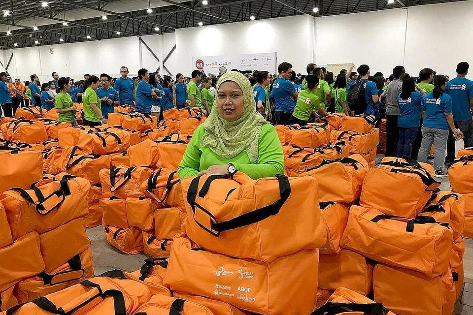 TEBAR IHSAN BUAT GOLONGAN MEMERLUKAN: Cik Suryati Wahid (atas) senangi kerja sukarela seperti menyiapkan beg cenderahati berisi makanan dan keperluan menjelang Tahun Baru Cina, yang mendekatkannya dengan warga emas memerlukan. - Foto STANDARD CHARTERED BANK