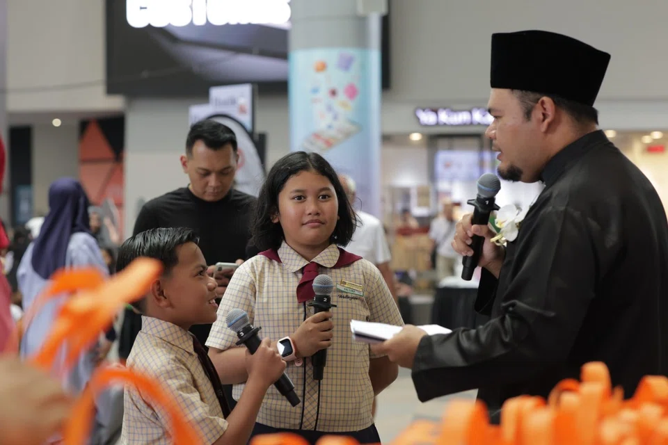 Dua pelajar dari Sekolah Rendah Wellington (dari kiri) Muhammad Noor Huzaifa Mohamed Nizam, dan Aalyana Aasiyah Muhammad Adib Kosnan, menjadi Wartawan Cilik di acara ‘Jejak Warisan, Raikan Bahasa’. Mereka dibimbing penyanyi, penyair dan Duta Bahasa, Noorhaqmal Mohd Noor atau lebih dikenali sebagai Aqmal N. (kanan) bagi menimba pengalaman dalam pengacaraan serta kemahiran komunikasi. 